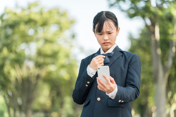 スマホを見て嫌な顔をする少女