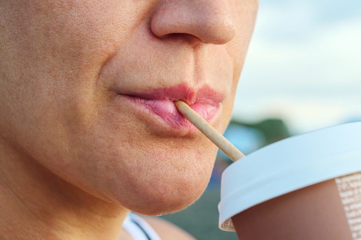 紙ストローでドリンクを飲む女性