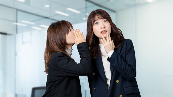 内緒の話を聞いて驚く女性・ビジネスウーマン
