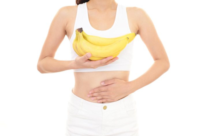 バナナを持ちつつ、お腹に手をあてる女性