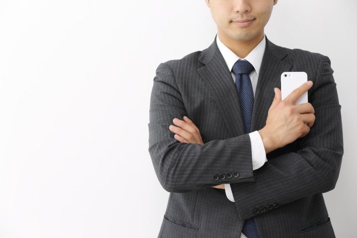スマートフォンを持ってたたずむビジネスマン