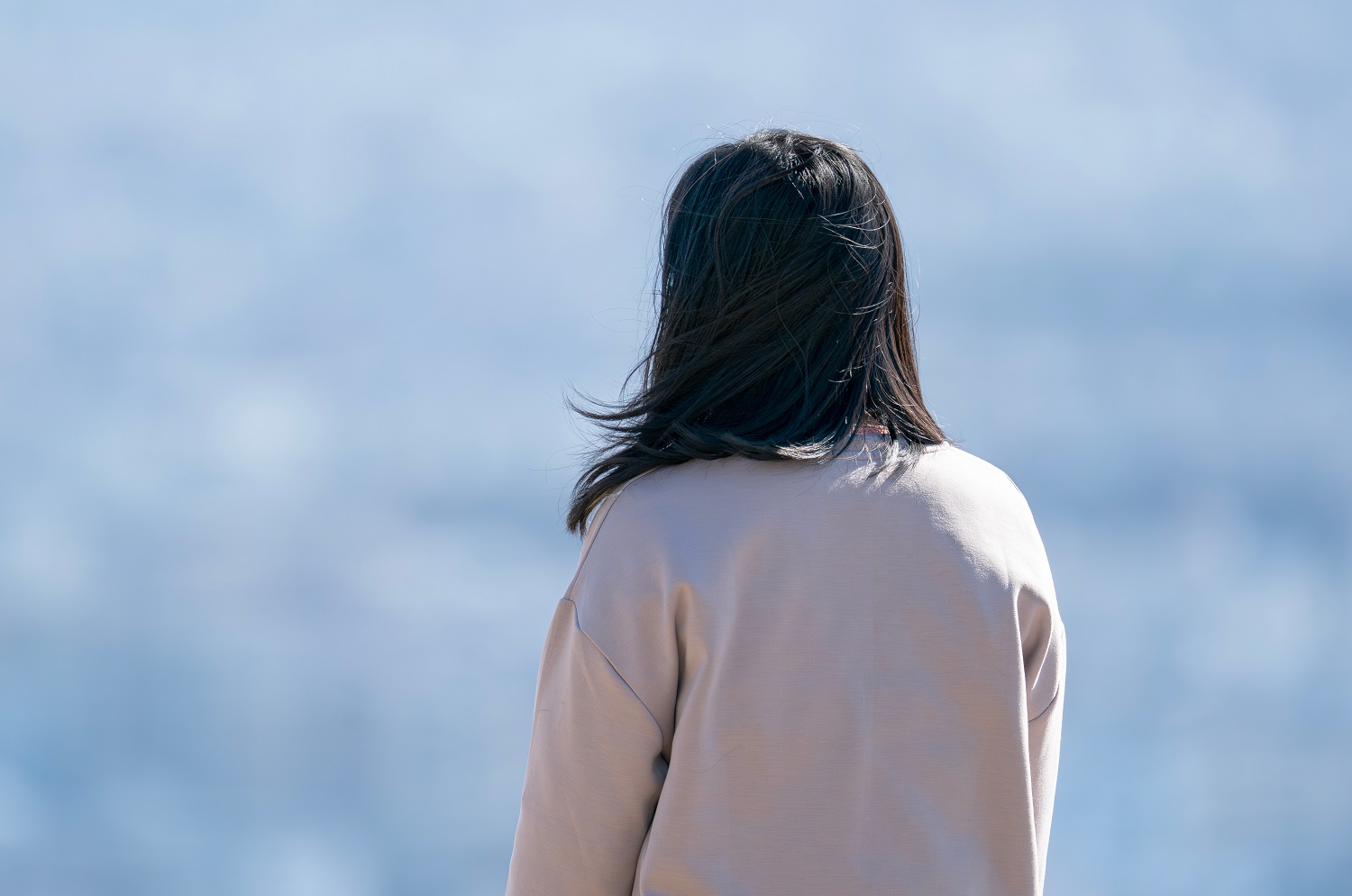 遠くを眺める女性の後ろ姿