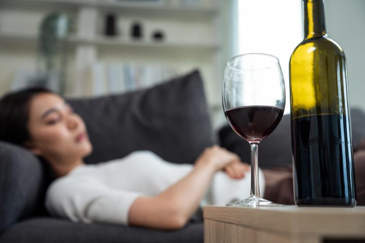 お酒を飲みつつソファで横たわる女性