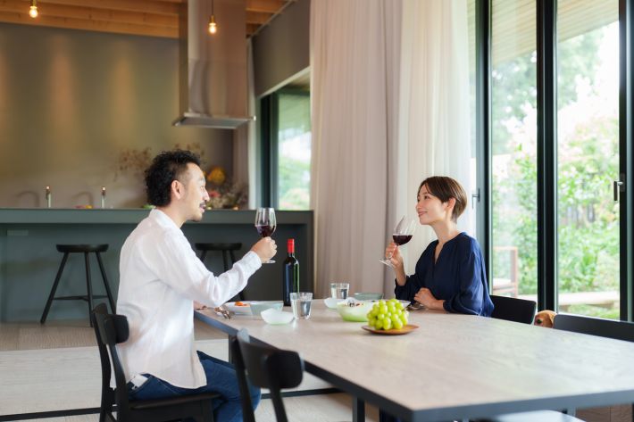 モダンなリビングダイニングで赤ワインを飲む夫婦