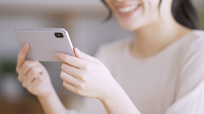 スマートフォンで動画を観る若い女性