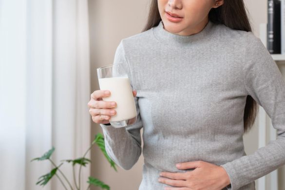 ミルク片手にお腹をおさえる女性