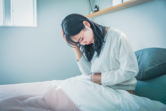 ベッド上でうなだれる女性