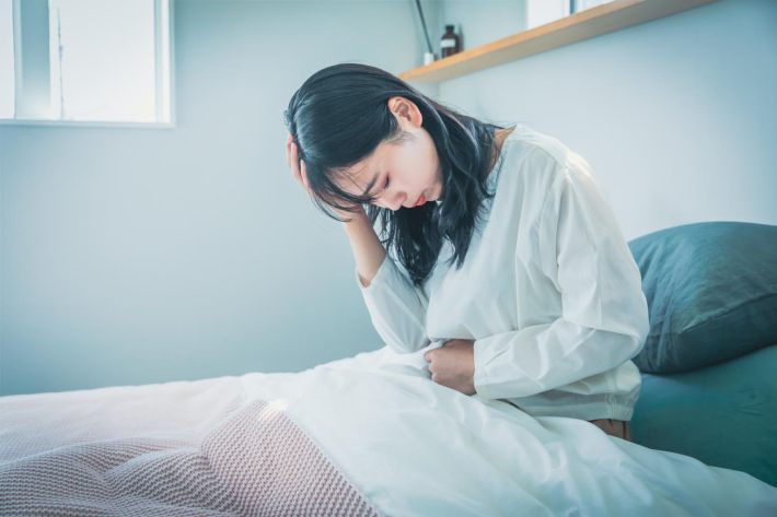 ベッド上でうなだれる女性