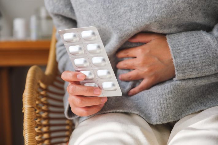 錠剤の包みを握りながらお腹に手をあてる女性