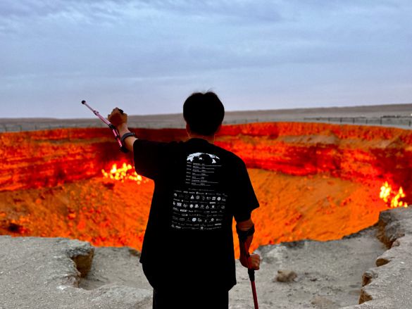 「地獄の門」の前に立ち、腕を上げる三代さん