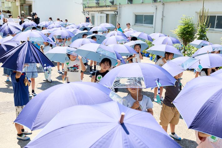 子ども日傘をさす児童たち