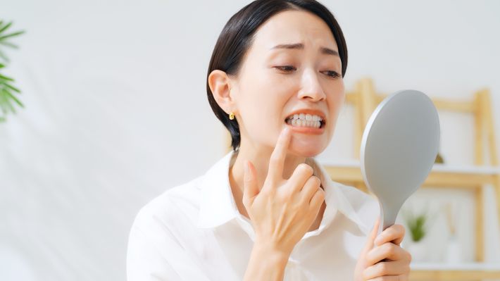 鏡で歯をチェックする女性