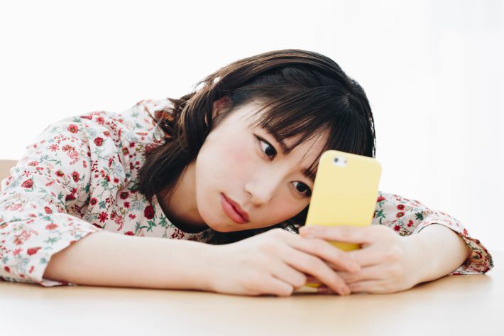 スマホを見て落ち込む女性